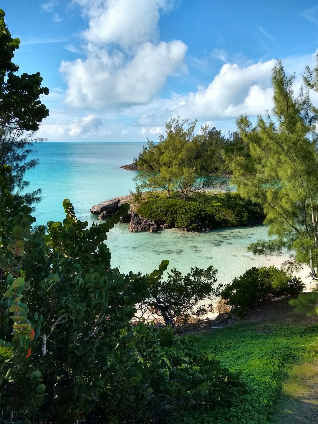 Baia tropicale con acqua turchese e isolotti rocciosi verdi.